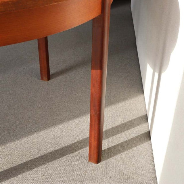Mid-century British vintage teak dining table leg with smooth wood grain and tapered design against neutral carpet and.