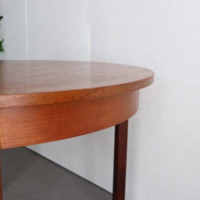 Vintage British mid-century dining table in warm teak with smooth rounded edge and slender tapered legs.