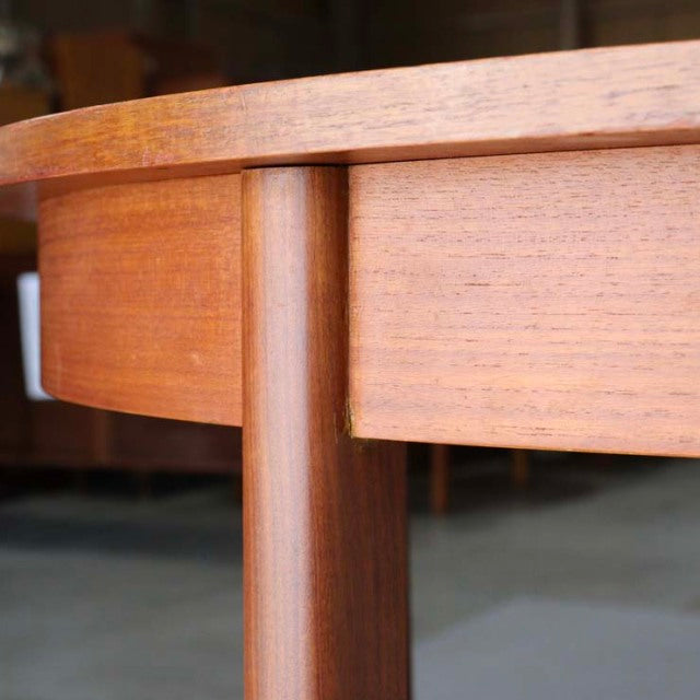 Mid-century British vintage teak dining table leg and apron showing smooth wood grain and rounded edge craftsmanship.