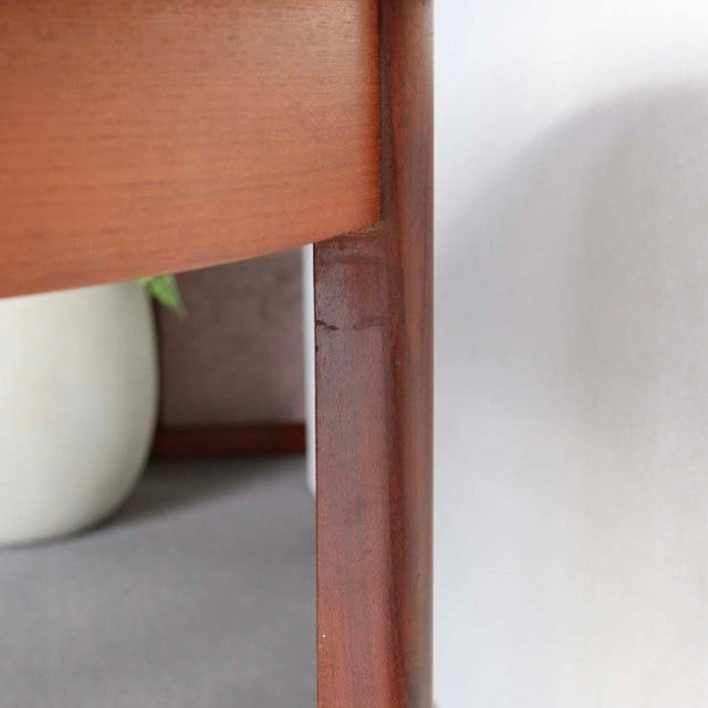 Close-up of vintage teak dining table leg showing rich wood grain and smooth mid-century British craftsmanship finish.