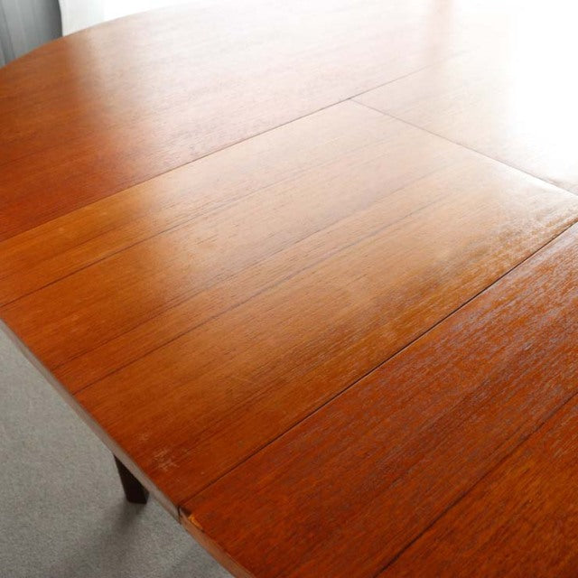 Mid-century British vintage teak dining table with rich wood grain and elegant tapered legs.