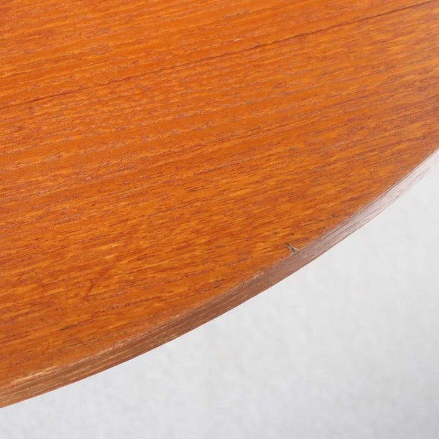 Close-up of vintage teak dining table edge showing smooth wood grain and warm mid-century British craftsmanship.