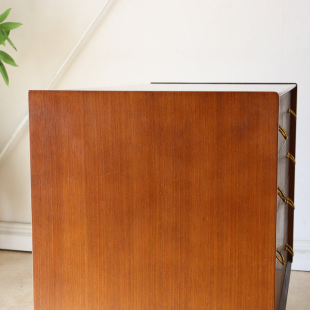 Vintage G-Plan teak 4-drawer chest with rich wood grain, sleek mid-century British design, and tapered legs from Denmark.