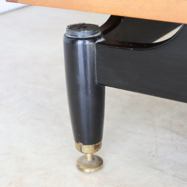 Close-up of black tapered wooden leg with brass foot, part of mid-century British G-plan teak chest or sideboard.
