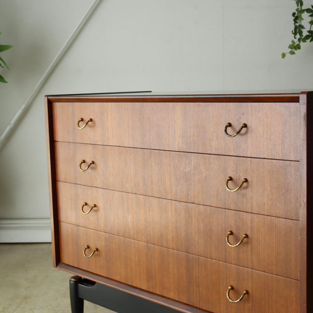 Vintage G-plan teak 4-drawer chest with brass handles, mid-century British design, sleek wood grain, and clean lines.