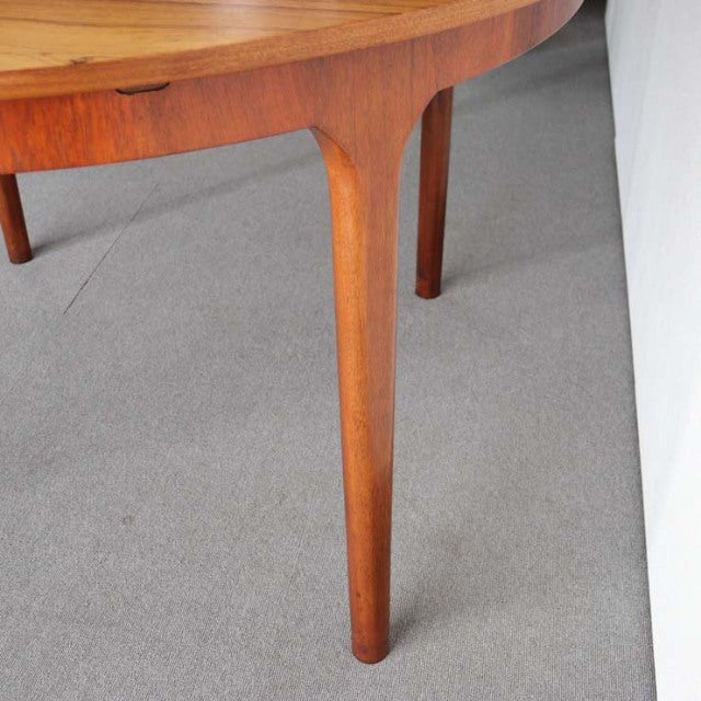 Mid-century British vintage teak round dining table featuring smooth grain and slender tapered legs.