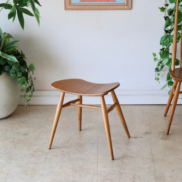 Vintage ERCOL mid-century teak butterfly stool with smooth curved seat and tapered legs in natural wood grain finish.