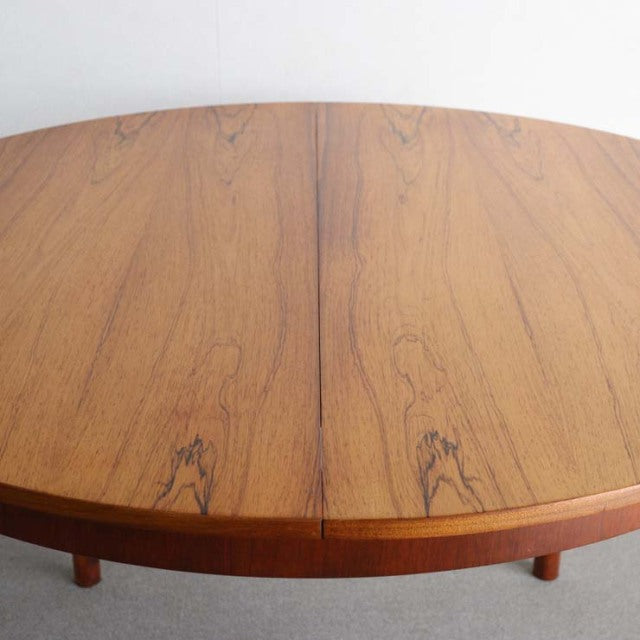 Vintage mid-century British teak round dining table with visible wood grain and sturdy tapered legs.