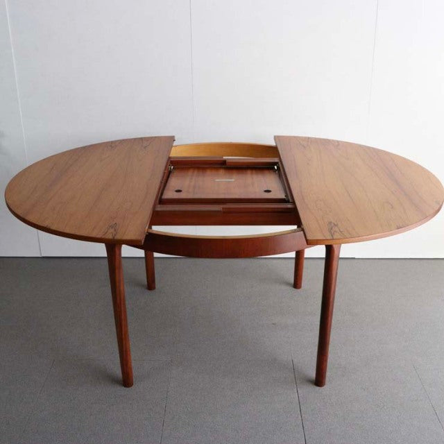 Mid-century British vintage teak round dining table by McIntosh with extending leaves and tapered legs.