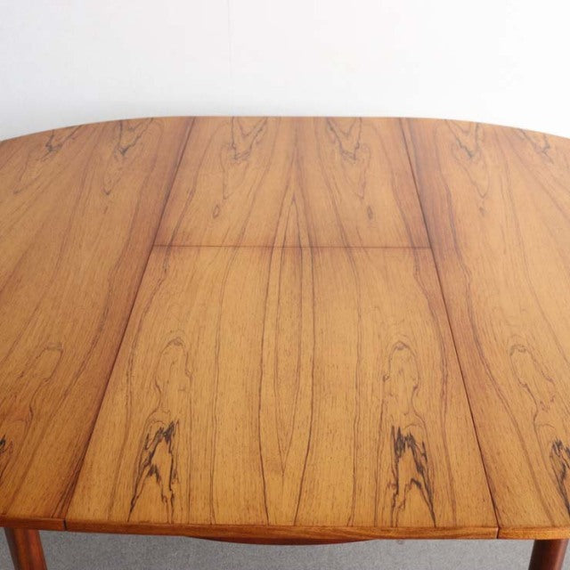 Vintage British mid-century teak round dining table with rich wood grain and tapered legs from McIntosh.