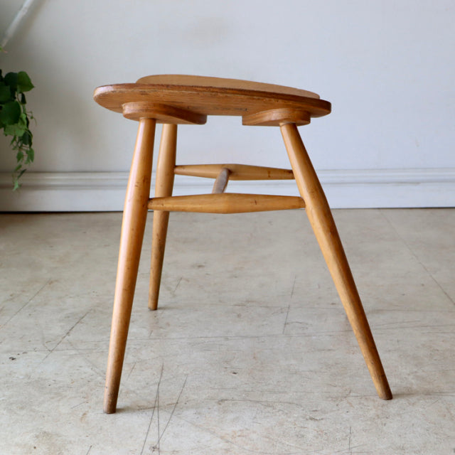 Mid-century British ERCOL Butterfly Stool in vintage teak with smooth wood grain, rounded edges, and three tapered legs.