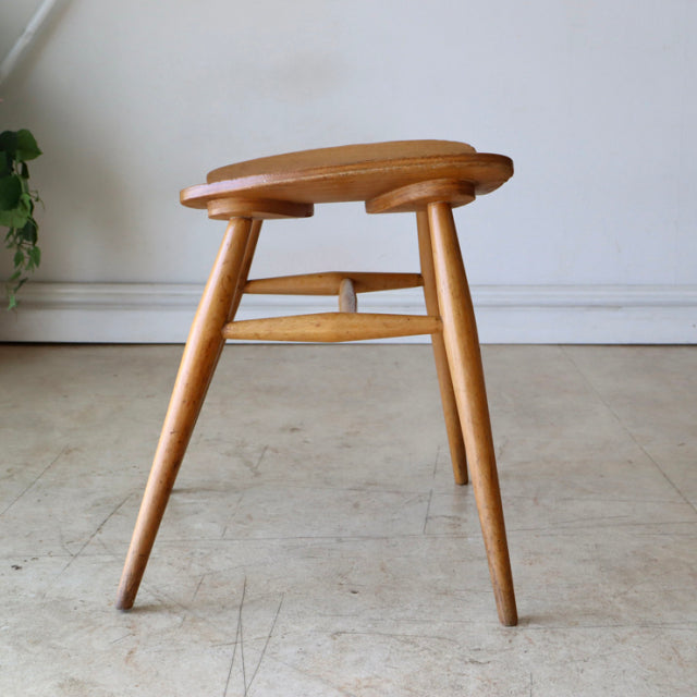 Mid-century British ERCOL butterfly stool in vintage teak with tapered legs and visible wood grain.