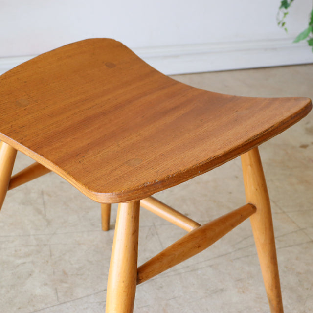 Mid-century British vintage ERCOL butterfly stool in teak with smooth curved seat and light wood legs.