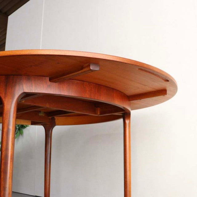 Vintage mid-century British teak round dining table with smooth wood grain and slender tapered legs, crafted by McIntosh.