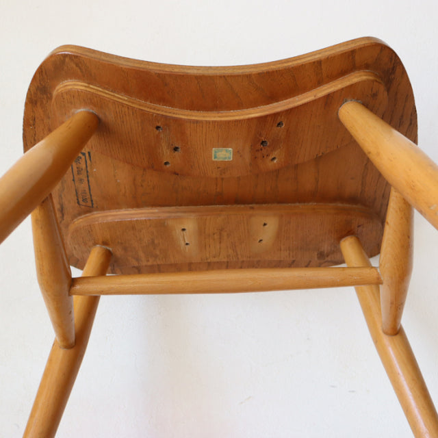 Underside view of vintage British mid-century Ercol butterfly stool in teak with smooth curved seat and turned legs showing.