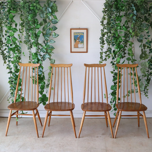 Set of four vintage Ercol Goldsmith high-back dining chairs in natural teak with slender spindle backs and angled legs,.