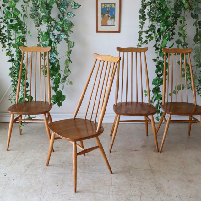 Set of four vintage Ercol Goldsmith mid-century teak dining chairs with high spindle backs and tapered legs, British design.