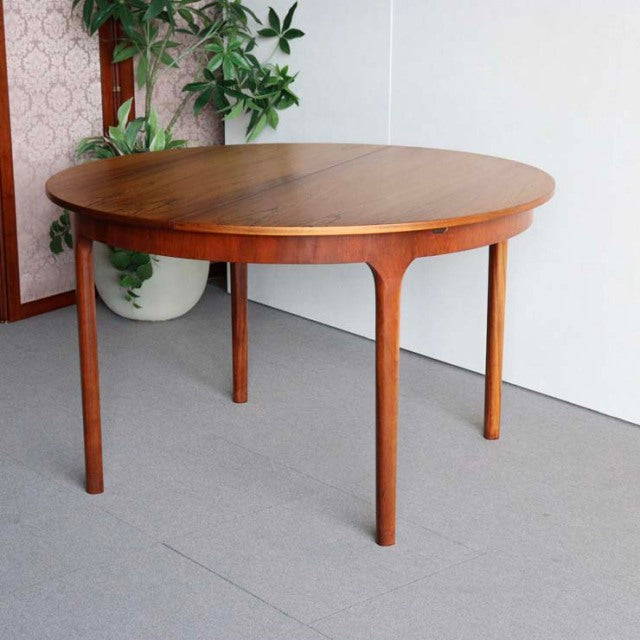 Round vintage teak dining table by McIntosh, British mid-century design with smooth wood grain and slender tapered legs.
