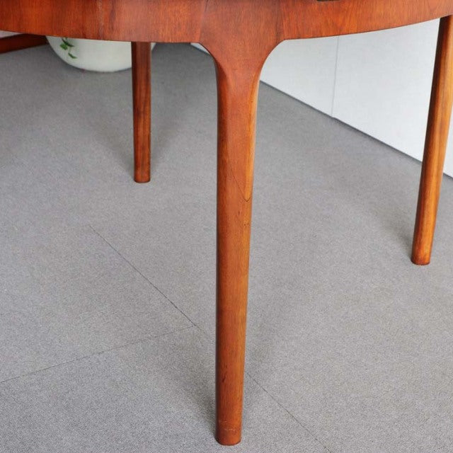 Mid-century British vintage teak round dining table leg with smooth wood grain and tapered design.