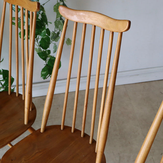 Set of four British vintage mid-century Ercol Goldsmith high-back dining chairs in natural teak with slender spindle backs.