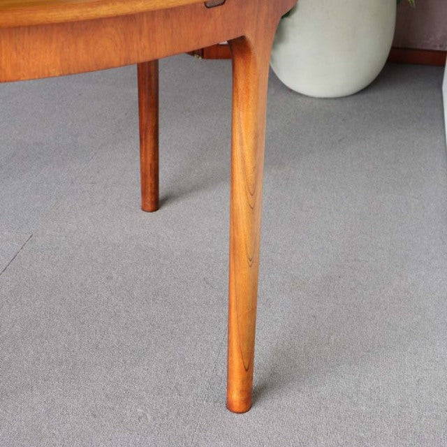 Mid-century British vintage teak dining table leg showing smooth wood grain and rounded tapering design.