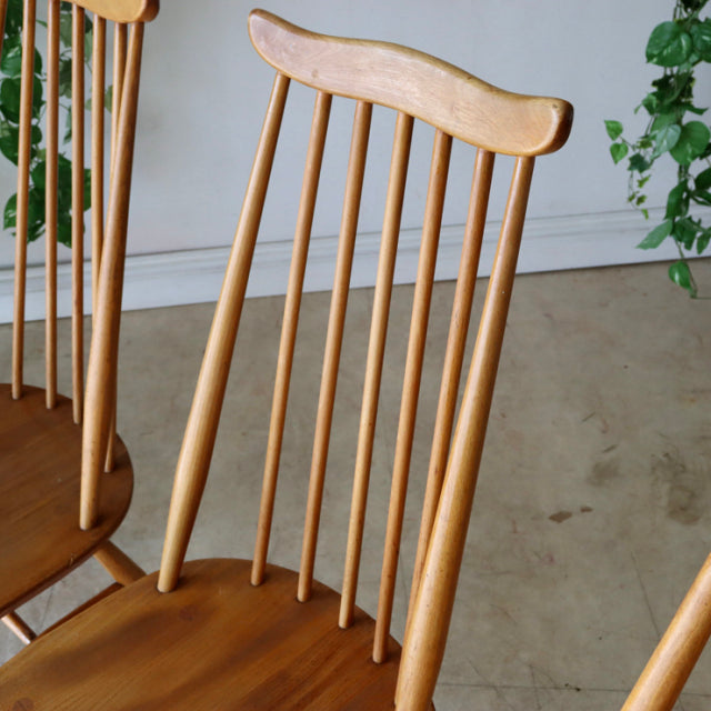 Set of four vintage Ercol Goldsmith highback dining chairs in natural teak wood with slender vertical spindles and smooth.