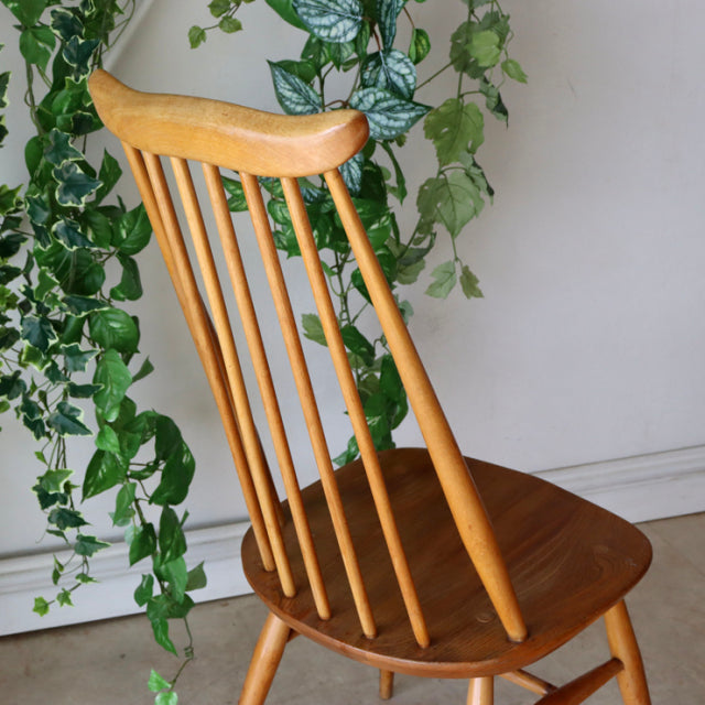 Set of four vintage British Ercol Goldsmith high-back dining chairs in natural teak with slender spindle backs and gently.