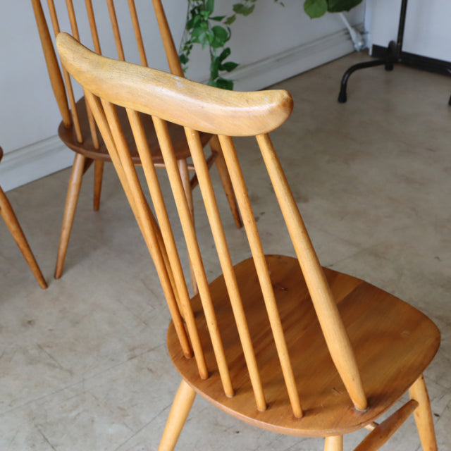 Set of four vintage mid-century British Ercol Goldsmith highback dining chairs in natural teak with slender spindle backs.