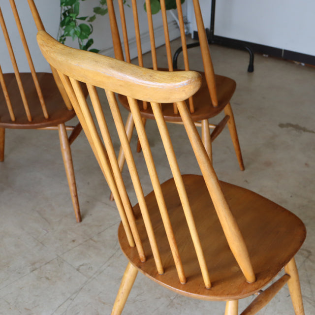 Set of four vintage Ercol Goldsmith high-back dining chairs in natural teak with slender spindle backs and tapered legs,.