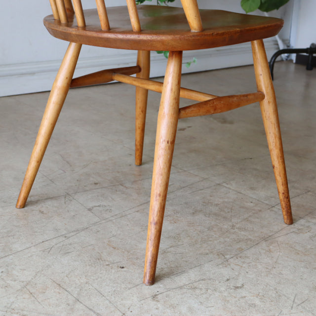 Mid-century British Ercol Goldsmith teak dining chair leg detail with natural wood grain and angled legs.