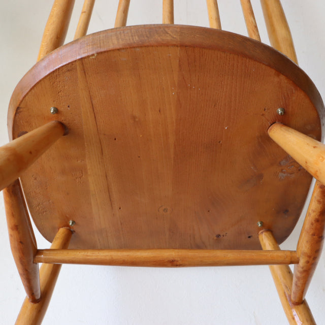 Underside view of vintage Ercol Goldsmith mid-century teak chair with smooth wood grain and round legs.
