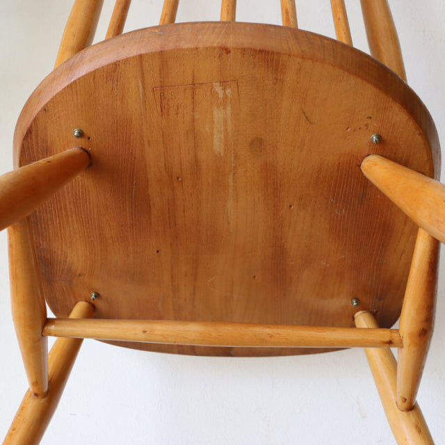 Underside view of a vintage British mid-century Ercol Goldsmith high-back chair in natural teak with smooth wood grain and.