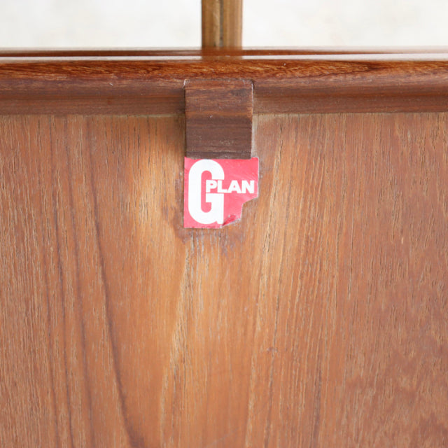 Close-up of vintage teak wood grain and G-Plan British mid-century furniture label on Danish dining table leg.