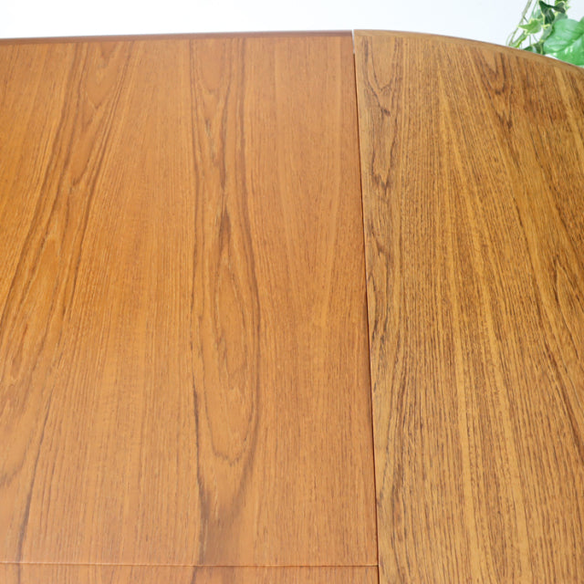 Vintage teak mid-century British G-Plan dining table with oval top and rich wood grain detail.