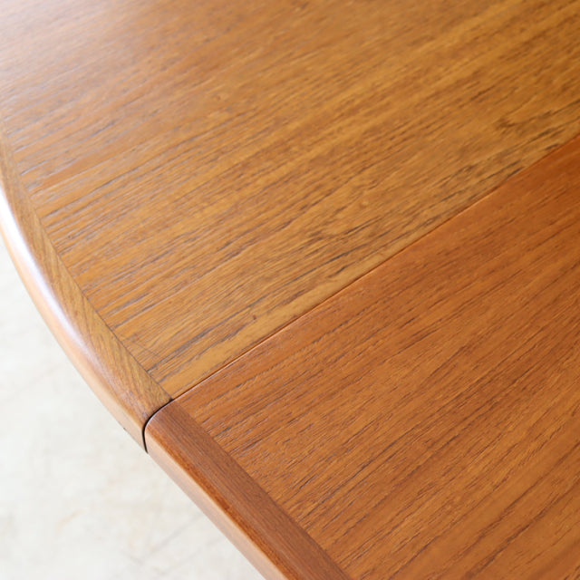Close-up of vintage British mid-century teak dining table corner showcasing rich wood grain and smooth rounded edge from.