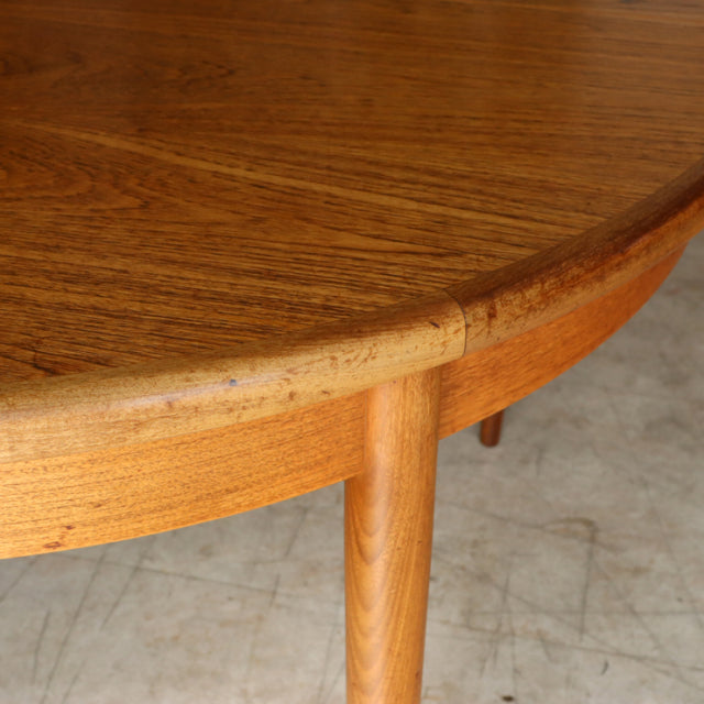 Vintage teak G-Plan dining table with rounded edge and cylindrical mid-century British legs showing rich wood grain.