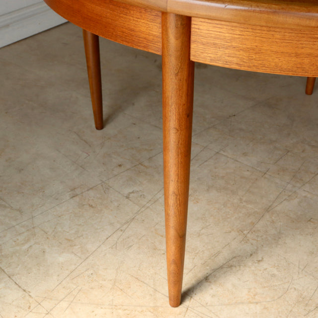 Mid-century British G-Plan vintage teak dining table leg with smooth wood grain and tapered design on concrete floor.