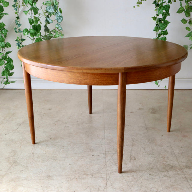Vintage mid-century British G-Plan dining table in warm teak with round top and tapered legs, showcasing rich wood grain and .