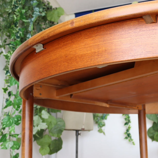 Vintage British G-Plan teak dining table with smooth rounded edge and slender mid-century tapered legs in warm teak wood.