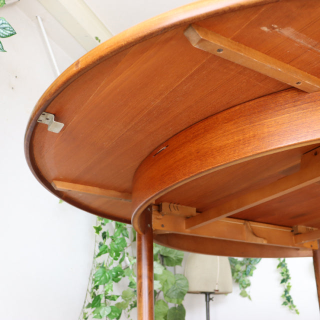 Vintage British G-Plan mid-century teak dining table underside showing sturdy wood grain and rounded legs.