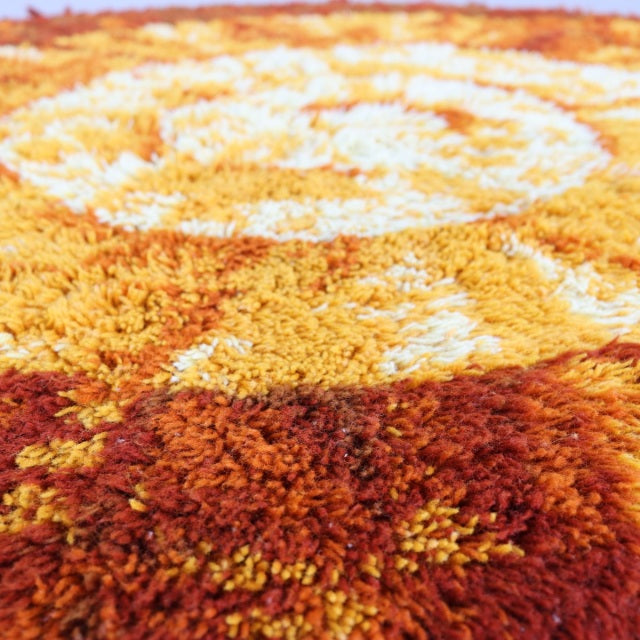 Vintage round mid-century rug with rich orange and mustard tones, featuring intricate textured patterns and dense plush.