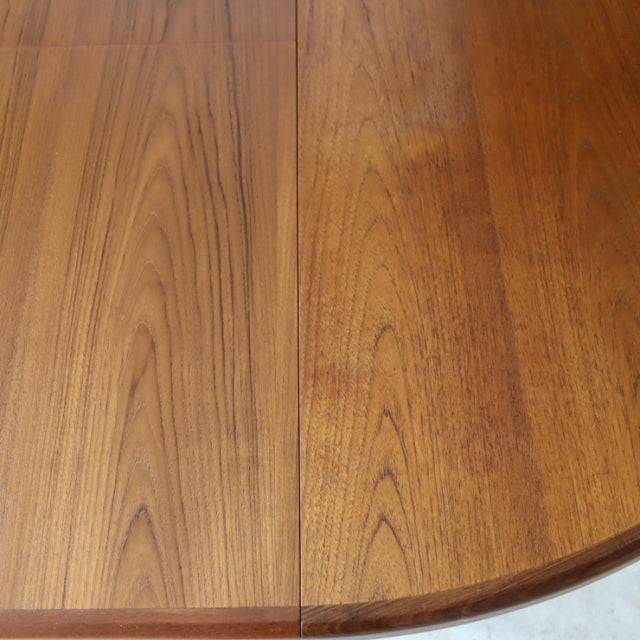 Vintage British mid-century G-PLAN round dining table top in warm teak with visible wood grain and smooth edges.