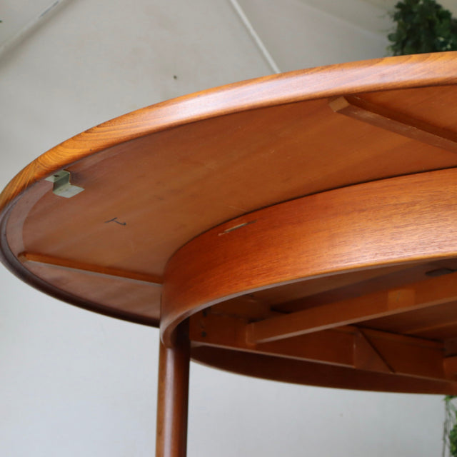 Round vintage teak dining table by British brand G-PLAN, mid-century design with smooth wood grain and slender legs from.