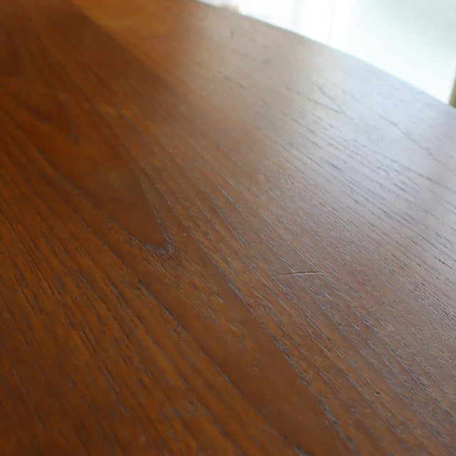 Close-up of vintage British mid-century G-Plan teak round dining table top showing rich wood grain and smooth finish.