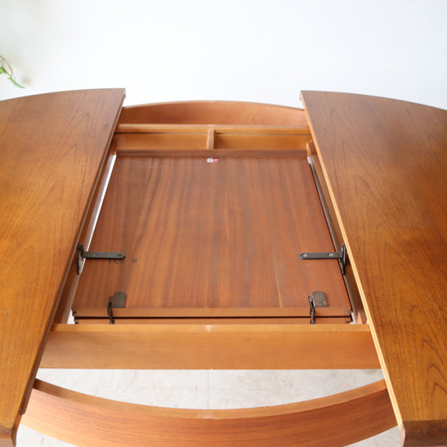 Mid-century British G-Plan vintage teak round dining table with rich wood grain and extending leaf mechanism.