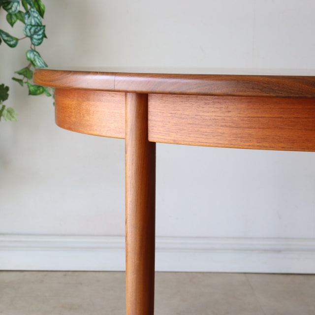 Vintage mid-century British G-Plan round dining table in warm teak with smooth wood grain and tapered cylindrical leg from.