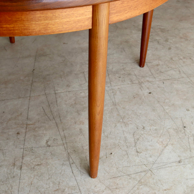 Vintage British G-Plan mid-century teak round dining table leg with smooth wood grain and tapered design.