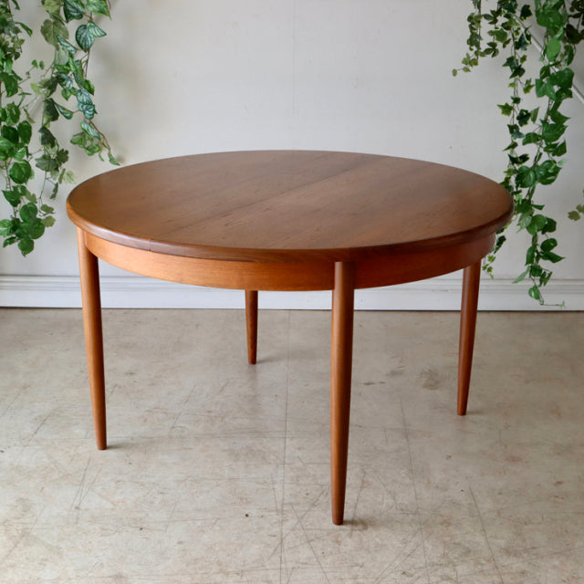 Vintage British G-Plan mid-century round teak dining table with clean wood grain and slender tapered legs.