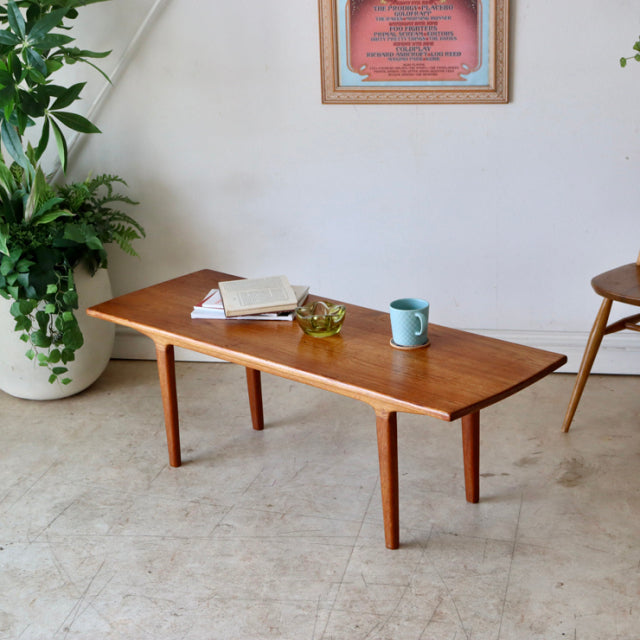 Mid-century British vintage teak coffee table with smooth wood grain top and tapered legs, Danish design influence.