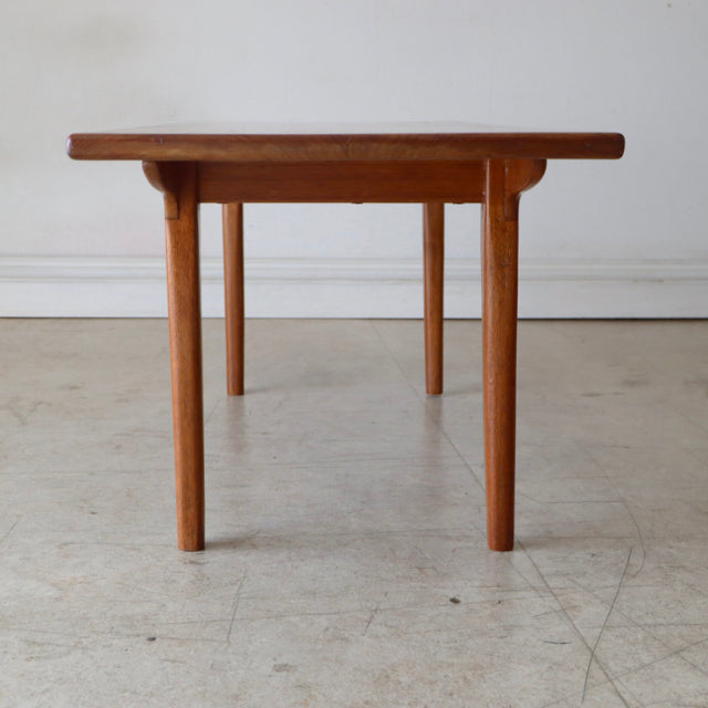 Mid-century British vintage teak coffee table with smooth wood grain and slender round legs.
